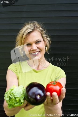 Image of Cute blond girl presenting vegetables