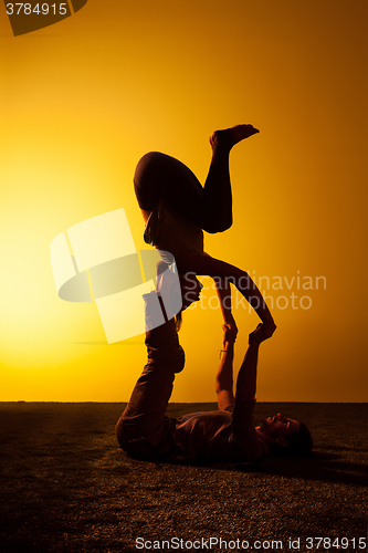 Image of Two people practicing yoga in the sunset light