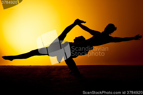 Image of Two people practicing yoga in the sunset light