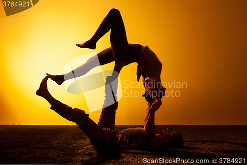 Image of Two people practicing yoga in the sunset light