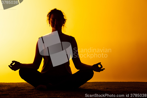 Image of The woman practicing yoga in the sunset light