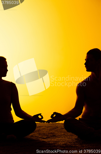 Image of Two people practicing yoga in the sunset light