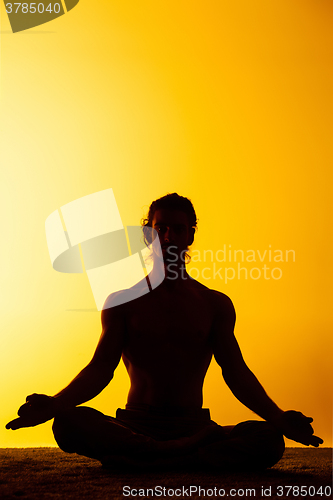 Image of The man practicing yoga in the sunset light