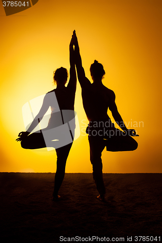 Image of Two people practicing yoga in the sunset light