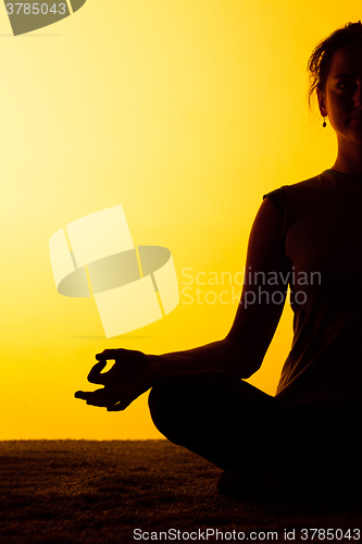 Image of The woman practicing yoga in the sunset light