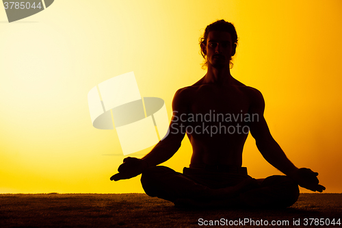 Image of The man practicing yoga in the sunset light