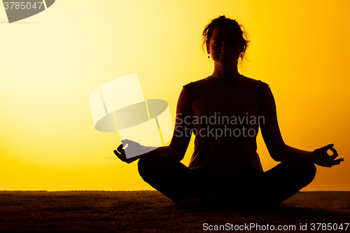 Image of The woman practicing yoga in the sunset light