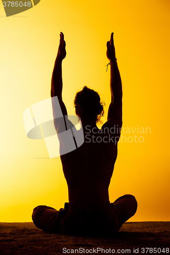 Image of The man practicing yoga in the sunset light