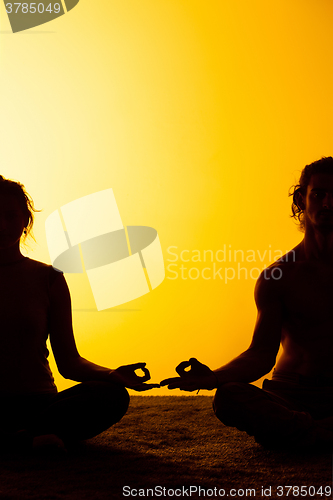 Image of Two people practicing yoga in the sunset light