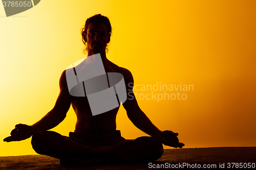 Image of The man practicing yoga in the sunset light
