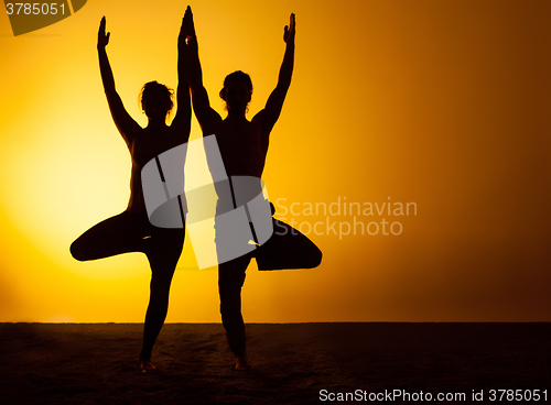 Image of Two people practicing yoga in the sunset light