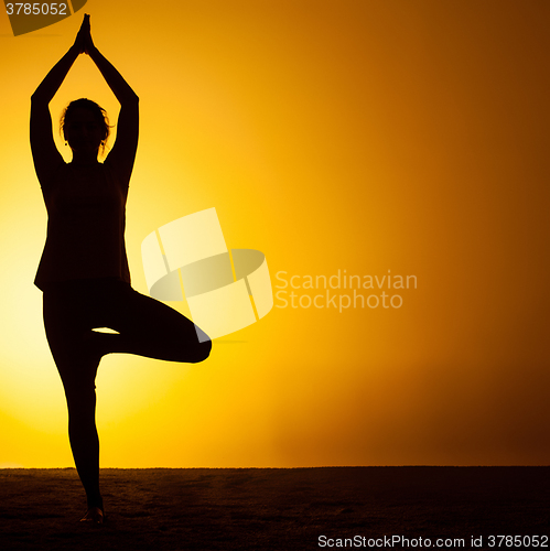 Image of The woman practicing yoga in the sunset light