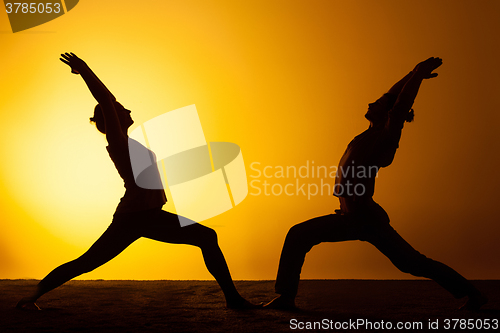 Image of Two people practicing yoga in the sunset light