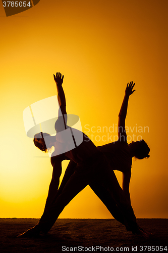 Image of Two people practicing yoga in the sunset light