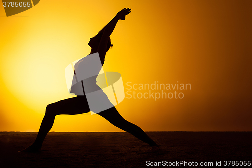 Image of The woman practicing yoga in the sunset light