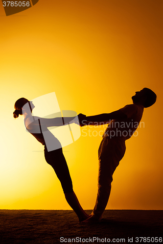 Image of Two people practicing yoga in the sunset light