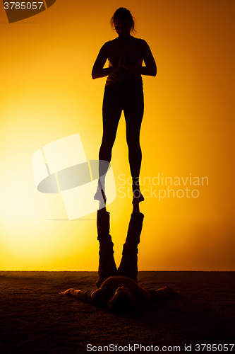 Image of Two people practicing yoga in the sunset light