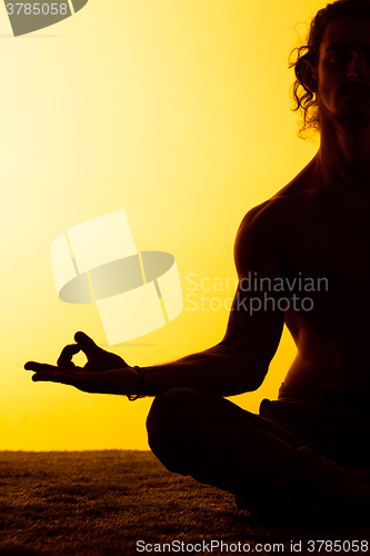 Image of The man practicing yoga in the sunset light