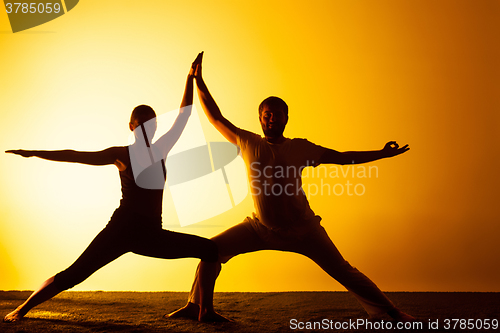 Image of Two people practicing yoga in the sunset light