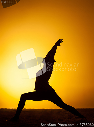 Image of The woman practicing yoga in the sunset light