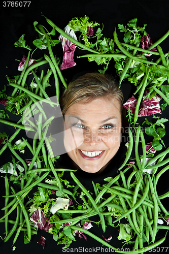 Image of Cute blond girl shot in studio with vegetables aroound the head