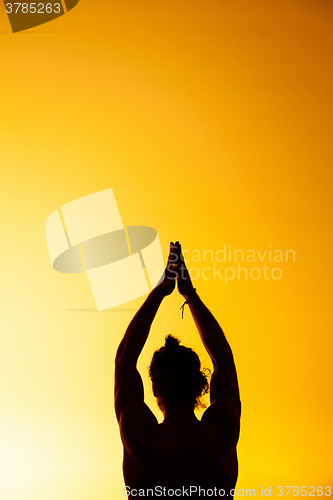 Image of The man practicing yoga in the sunset light