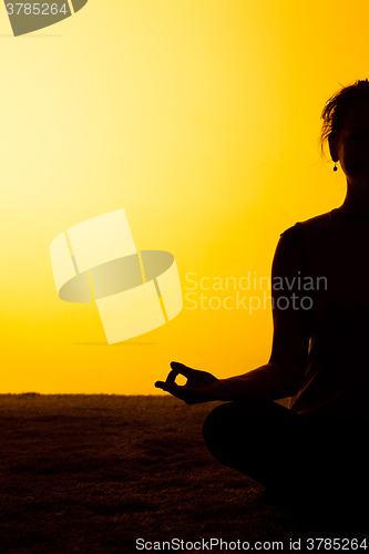 Image of The woman practicing yoga in the sunset light