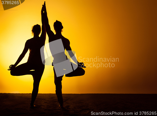 Image of Two people practicing yoga in the sunset light