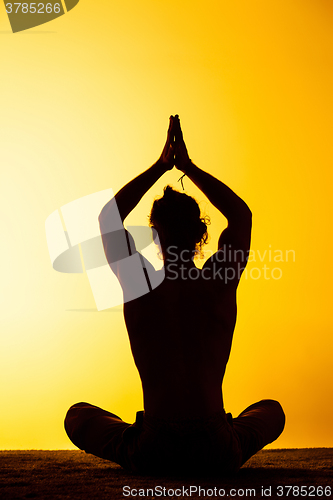 Image of The man practicing yoga in the sunset light