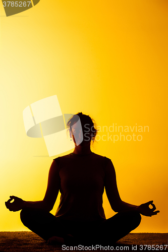 Image of The woman practicing yoga in the sunset light