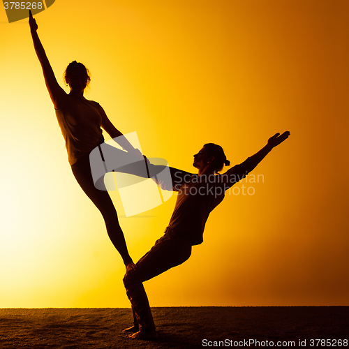 Image of Two people practicing yoga in the sunset light