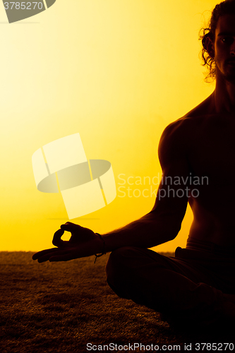 Image of The man practicing yoga in the sunset light