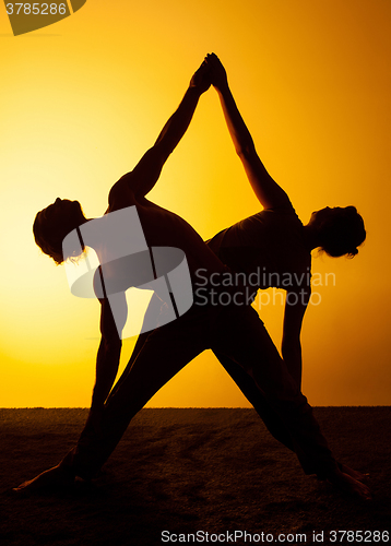 Image of Two people practicing yoga in the sunset light