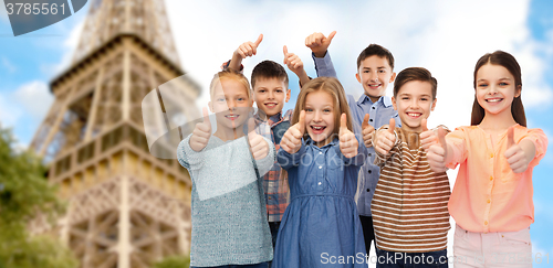 Image of happy children showing thumbs up over eiffel tower