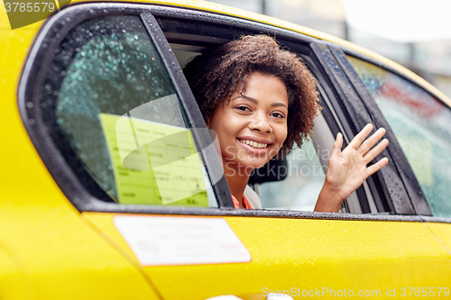 Image of happy african american woman driving in taxi