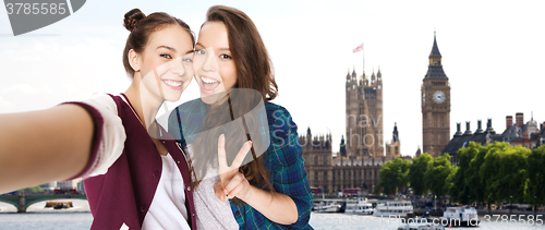 Image of friends taking selfie and showing peace in london