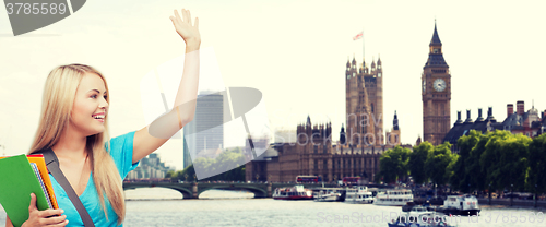 Image of student with folders waving hand over london city