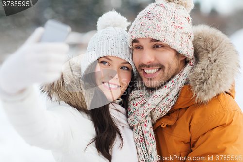 Image of happy couple taking selfie by smartphone in winter