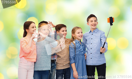 Image of happy children with smartphone and selfie stick