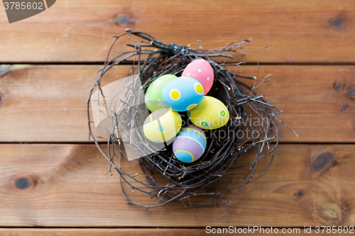 Image of close up of colored easter eggs in nest on wood