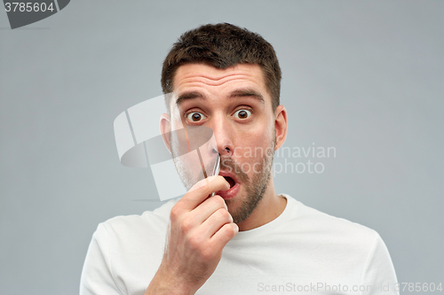 Image of man with tweezers tweezing hair from nose