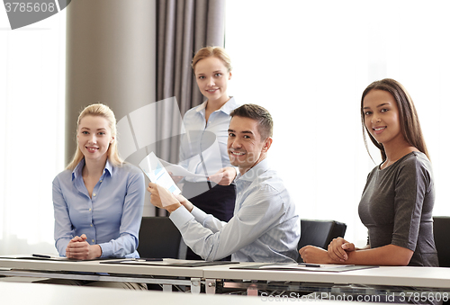 Image of smiling business people with papers in office