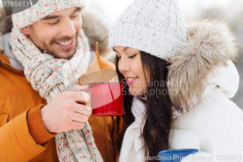 Image of happy couple with tea cups over winter landscape