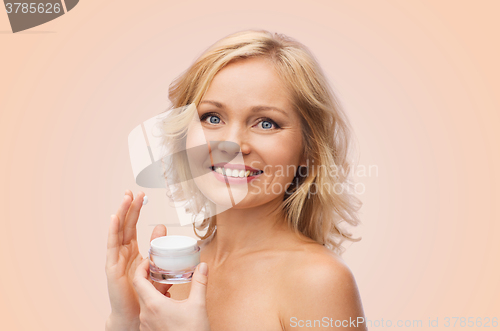 Image of happy woman applying cream to her face