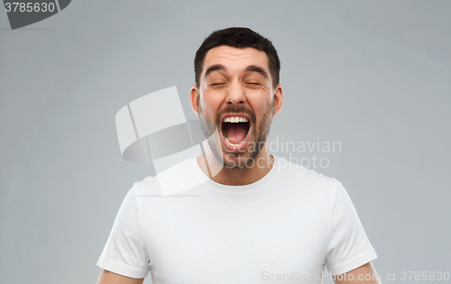 Image of crazy shouting man in t-shirt over gray background