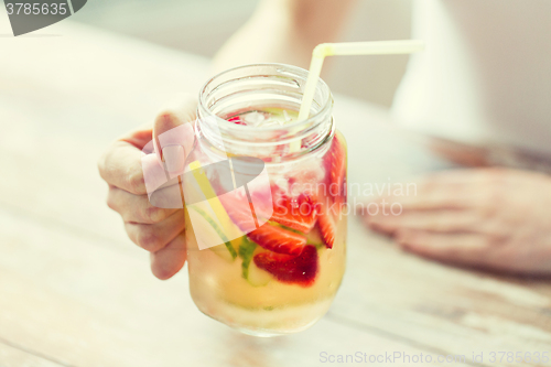 Image of close up of woman holding glass with fruit water