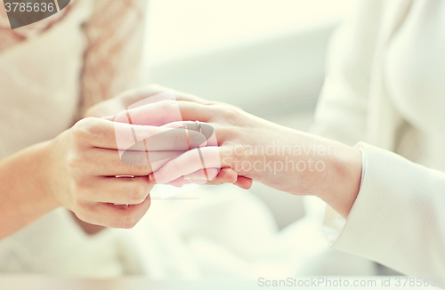 Image of close up of lesbian couple hands with wedding ring