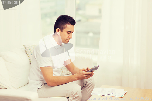 Image of man with papers and calculator at home