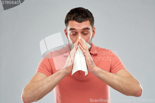 Image of sick man with paper napkin blowing nose