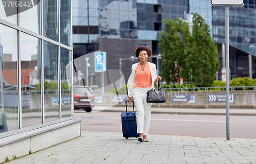 Image of happy young african woman with travel bag in city